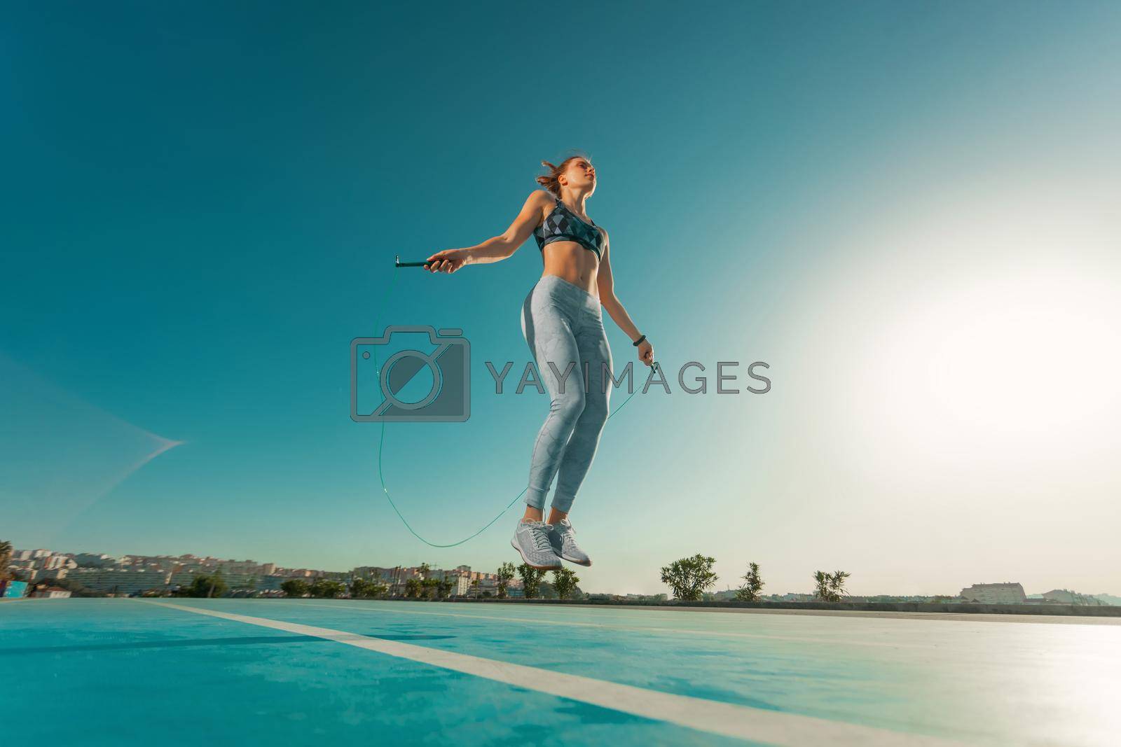 Royalty free image of Young sportswoman training jumping on an agility ladder coordinating outdoors by MikeOrlov