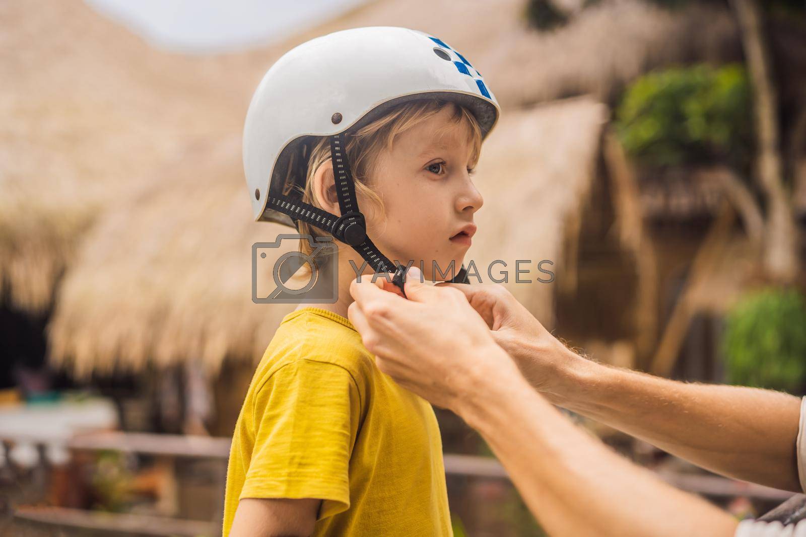 Royalty free image of Trainer helps the boy to wear helmet before training skate board by galitskaya
