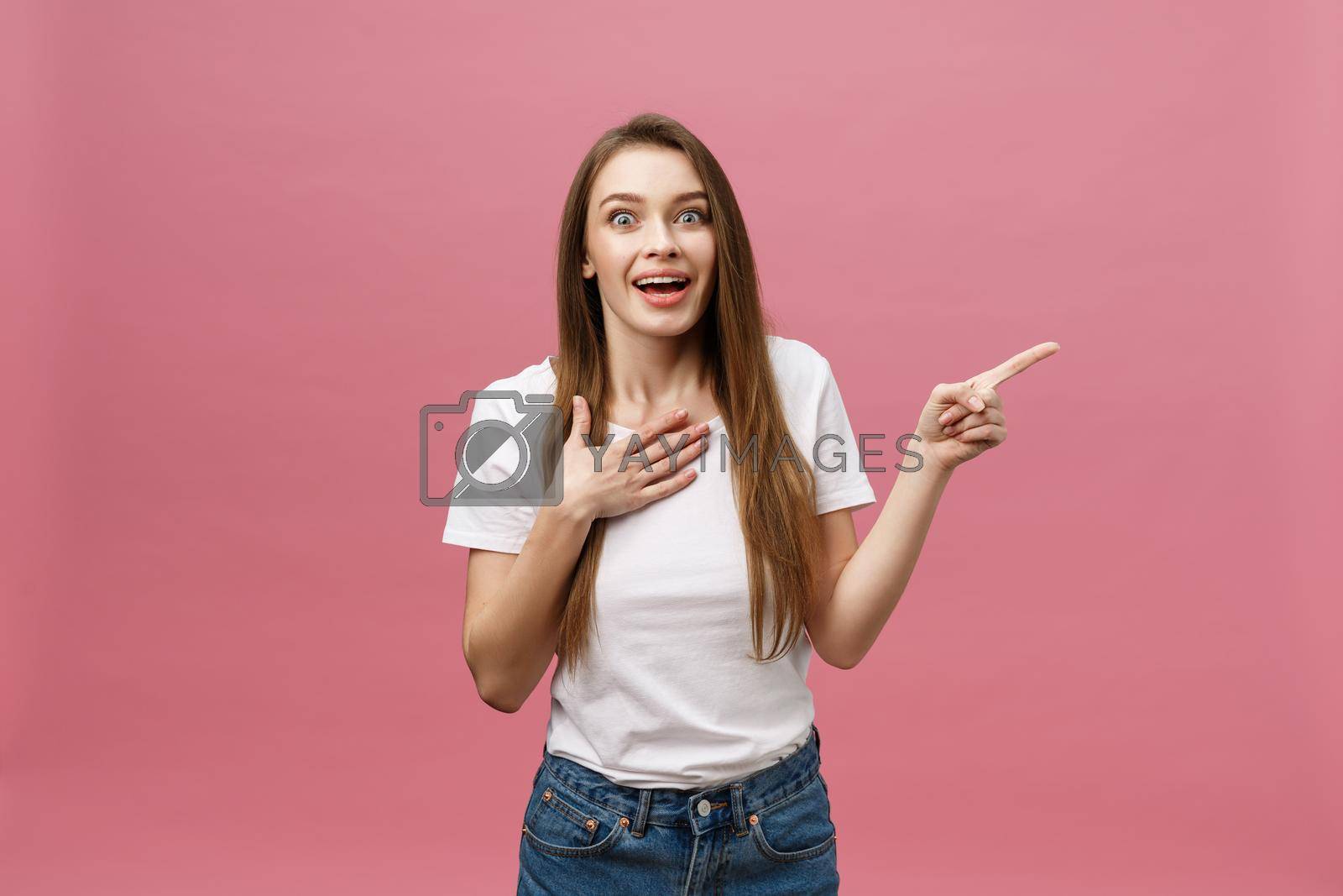 Royalty free image of Woman pointing finger at camera and toothy smiling. Expression emotion and feelings concept. Studio shot, isolated on pink background by Benzoix
