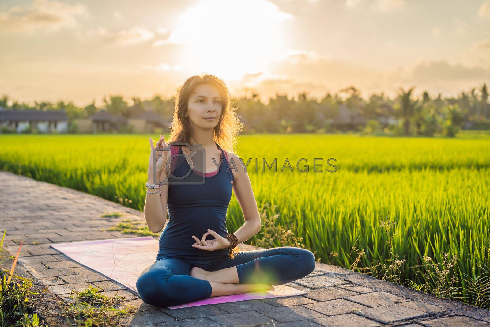Royalty free image of Young woman practice yoga outdoor in rice fields in the morning during wellness retreat in Bali by galitskaya