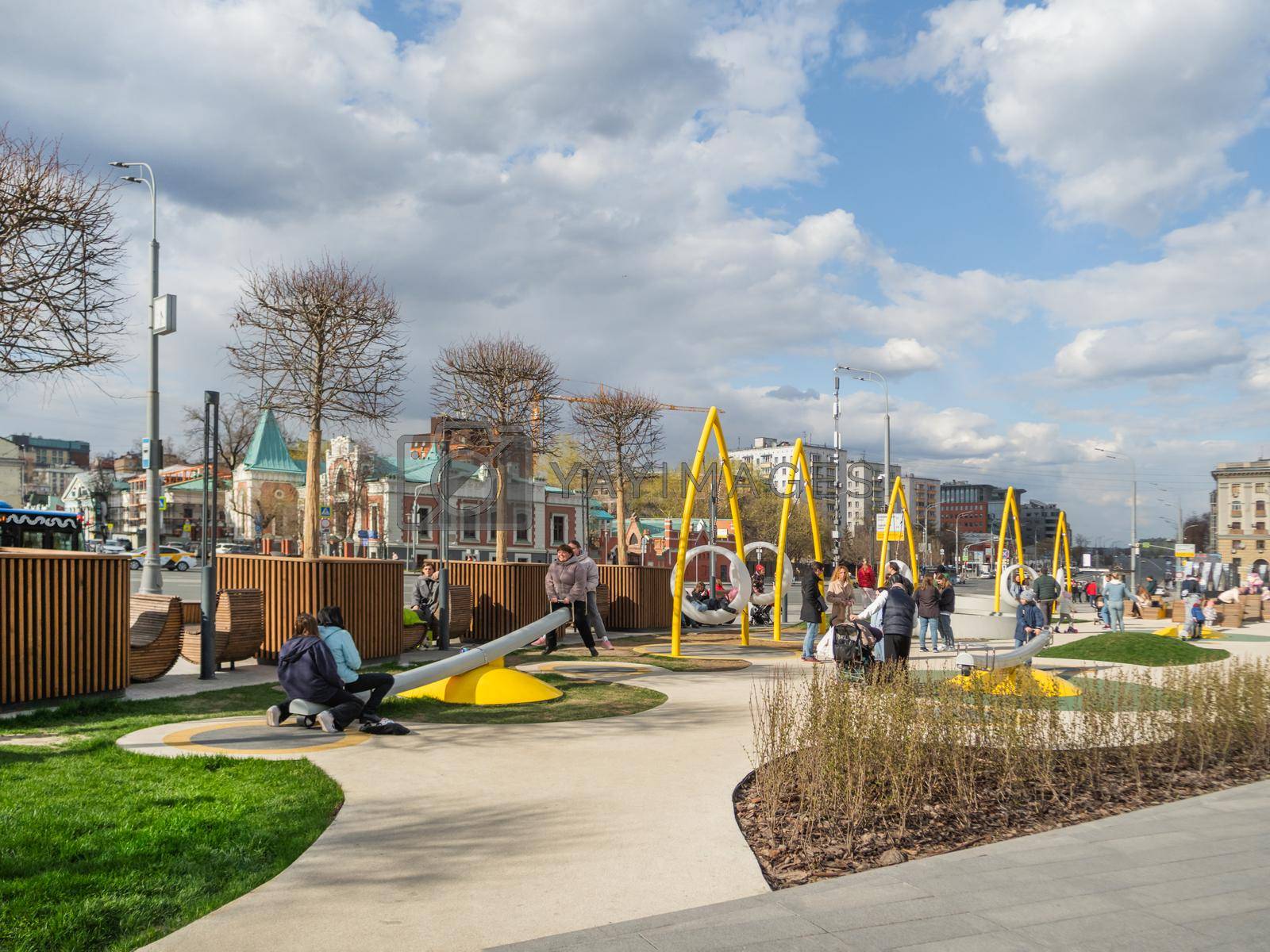 Royalty free image of MOSCOW, RUSSIA - May 01, 2022. Local people and tourists have a rest on playground of square near Paveletsky railway. Modern urban architecture. by aksenovko