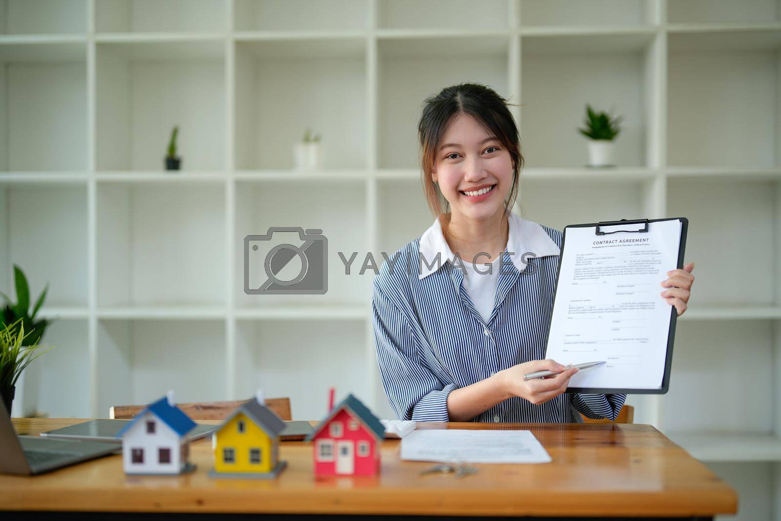 Royalty free image of Portrait real estate agent adviser show contract agreement on workplace by nateemee