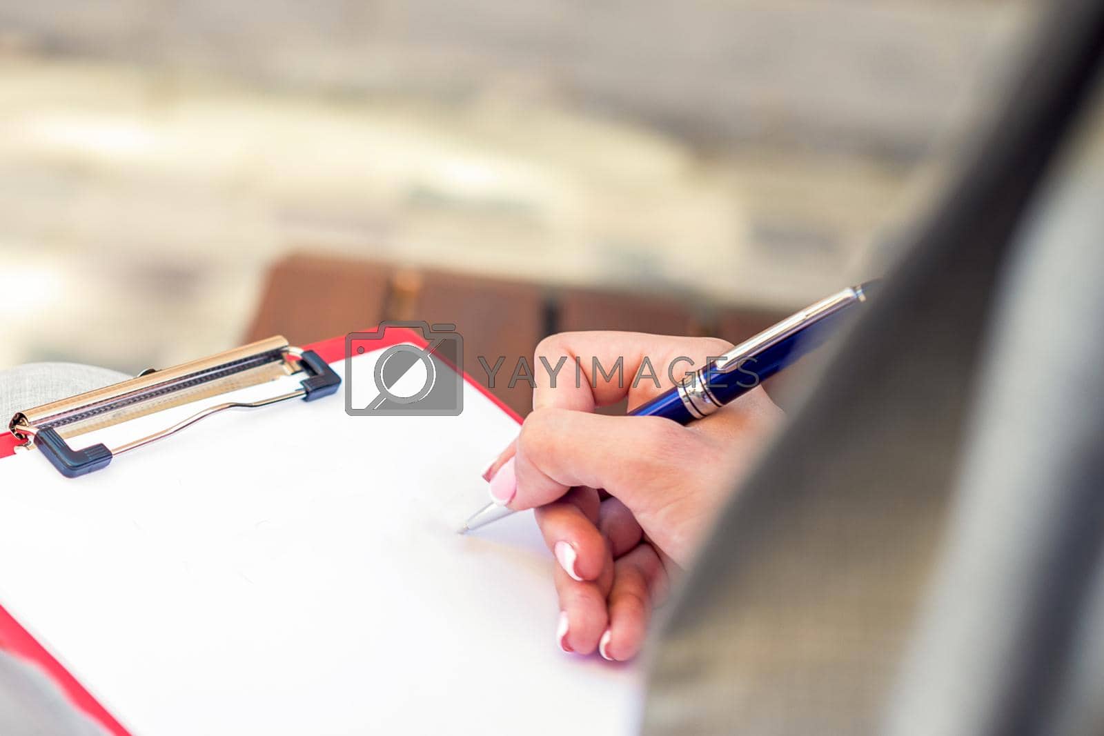 Royalty free image of Female hand writing in blank paper by okskukuruza