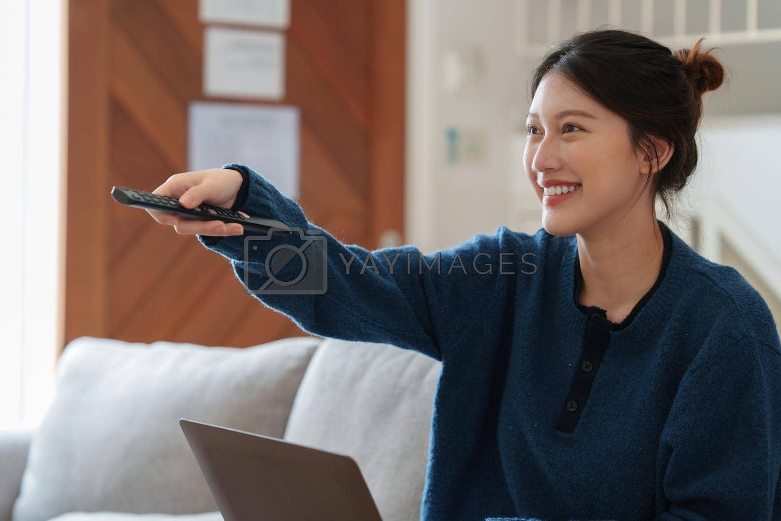 Royalty free image of Excited young Asian woman watching television programs with remote controller. Lifestyle and spends leisure at home. by itchaznong