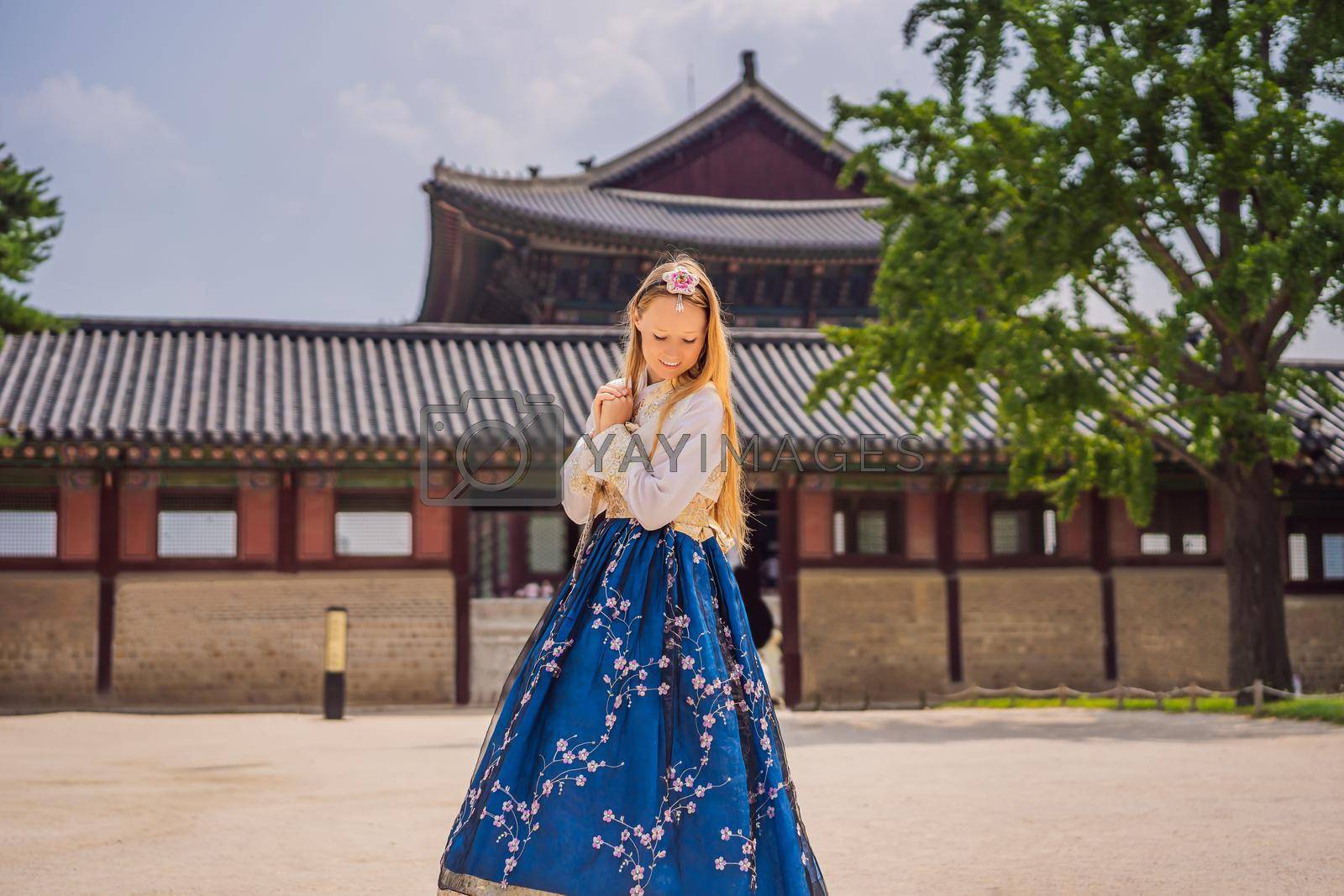 Royalty free image of Young caucasian female tourist in hanbok national korean dress at Gyeongbokgung Palace. Travel to Korea concept. National Korean clothing. Entertainment for tourists - trying on national Korean clothing by galitskaya