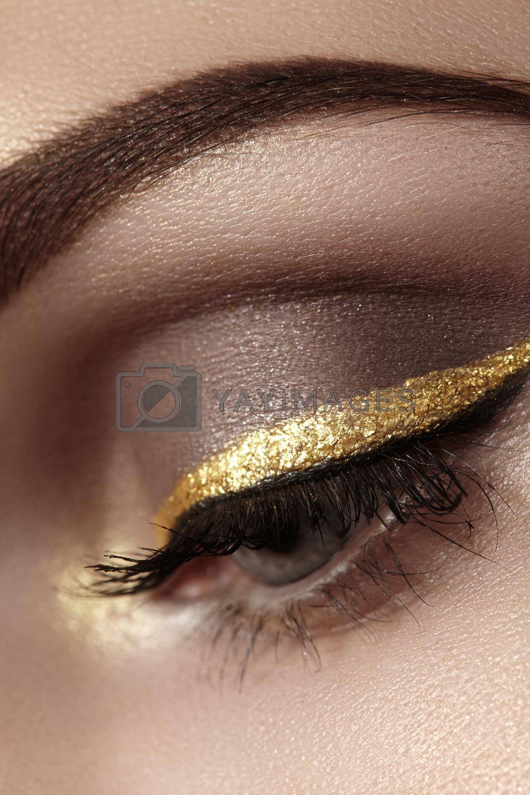 Royalty free image of Beautiful macro shot of female eye with ceremonial makeup. Perfect shape of eyebrows, eyeliner and gold line on eyelid by MarinaFrost