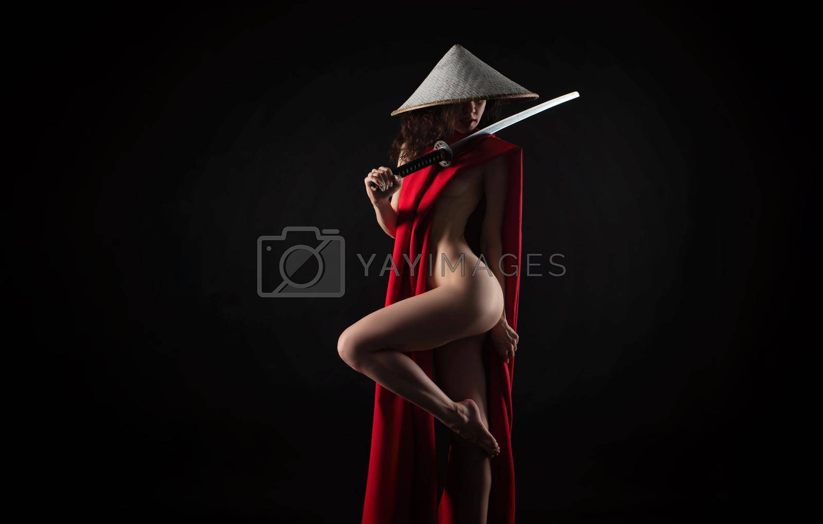 Royalty free image of naked slender woman in a red cape and an Asian hat with a katana in her hand image of a samurai by Rotozey