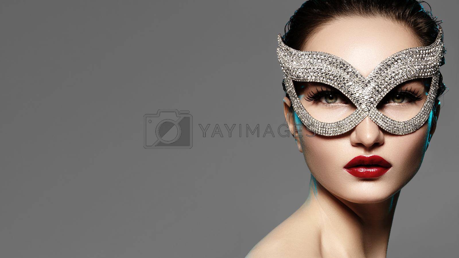 Royalty free image of Beautiful Model with Fashion Lips Makeup Wearing Bright Brilliant Mask. Masquerade Style Woman. Holiday Celebration Look by MarinaFrost
