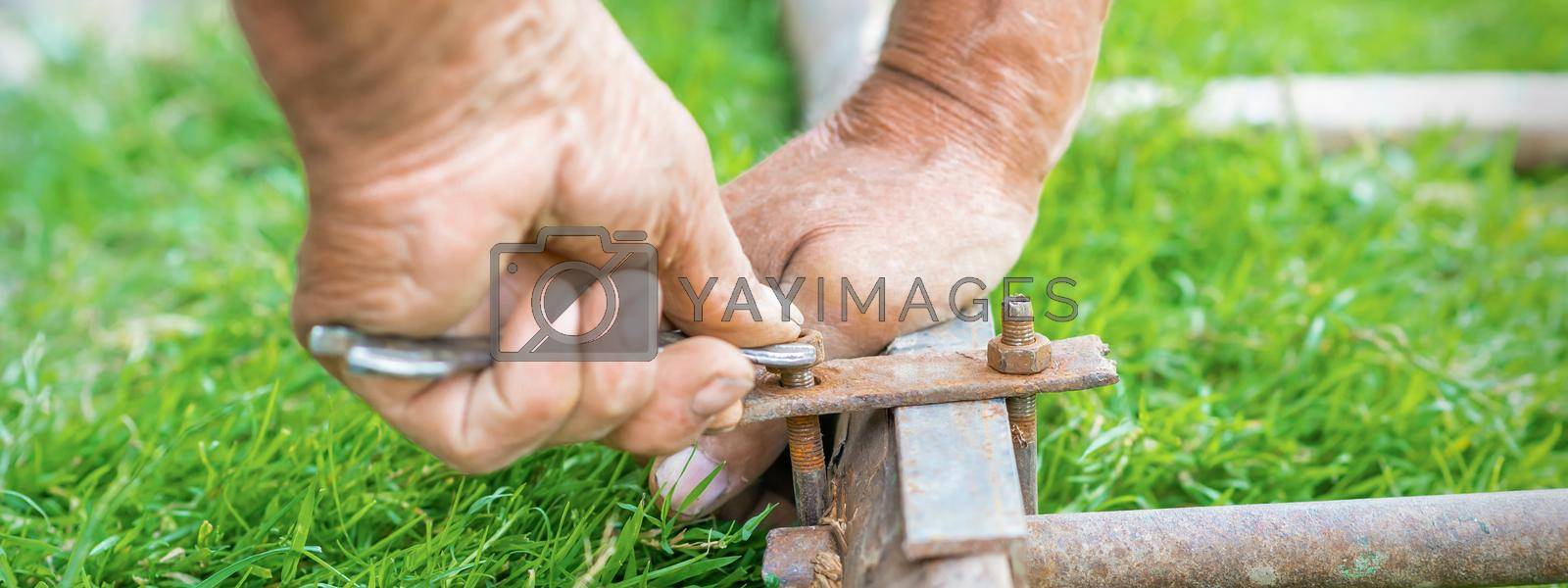 Royalty free image of Elderly man twists the nut by wrench by okskukuruza