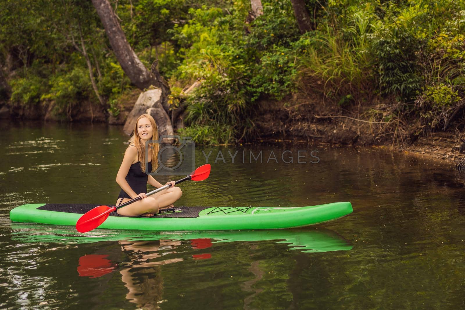 Royalty free image of SUP Stand up paddle board woman paddle boarding on lake standing happy on paddleboard on blue water. Action Shot of Young Woman on Paddle Board by galitskaya