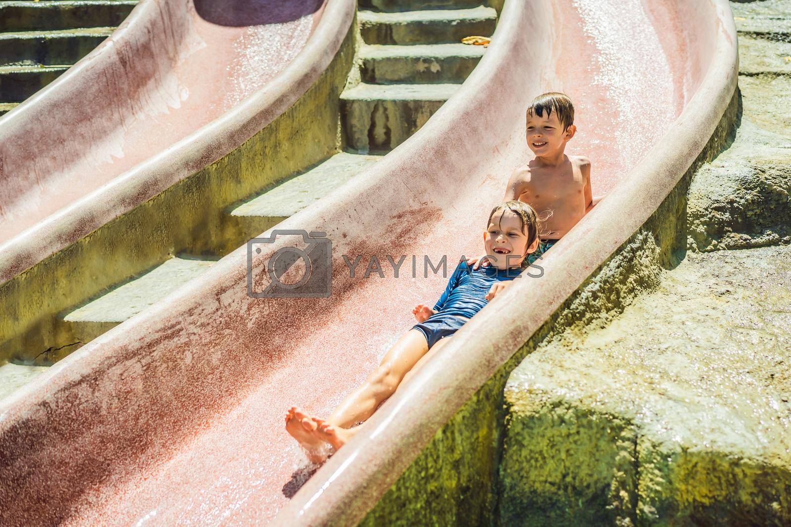 Royalty free image of Children ride a water slide in a water park. Happy childhood by galitskaya