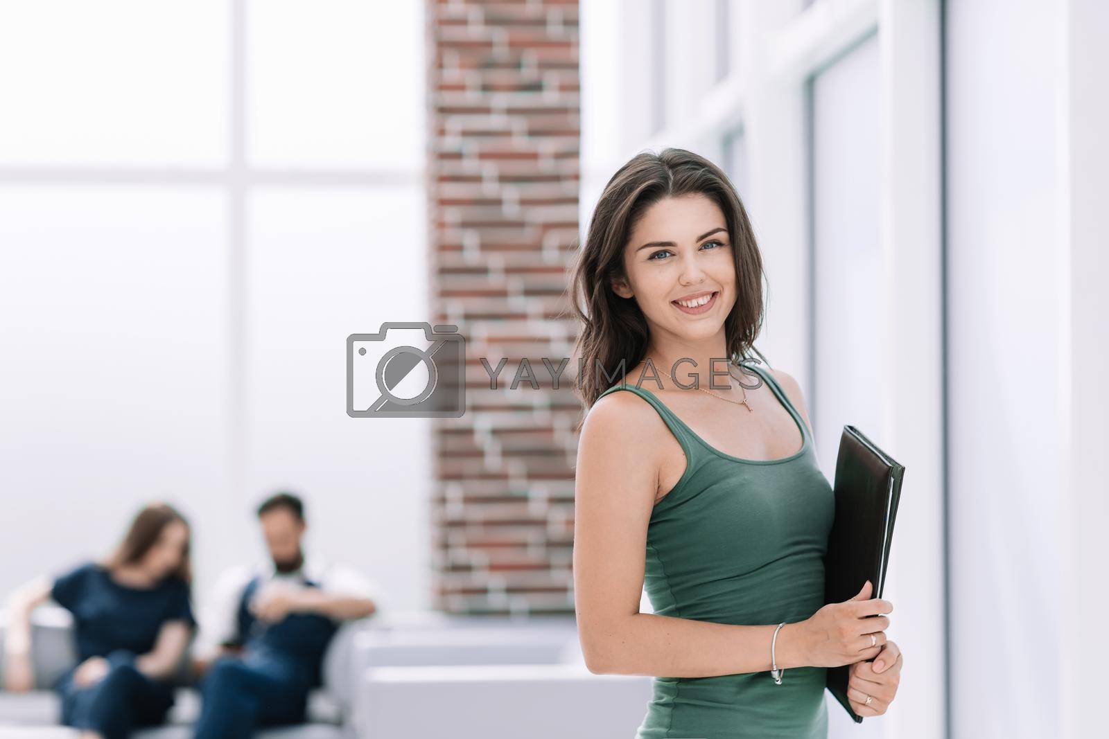 Royalty free image of young business woman with clipboard standing in office lobby by SmartPhotoLab
