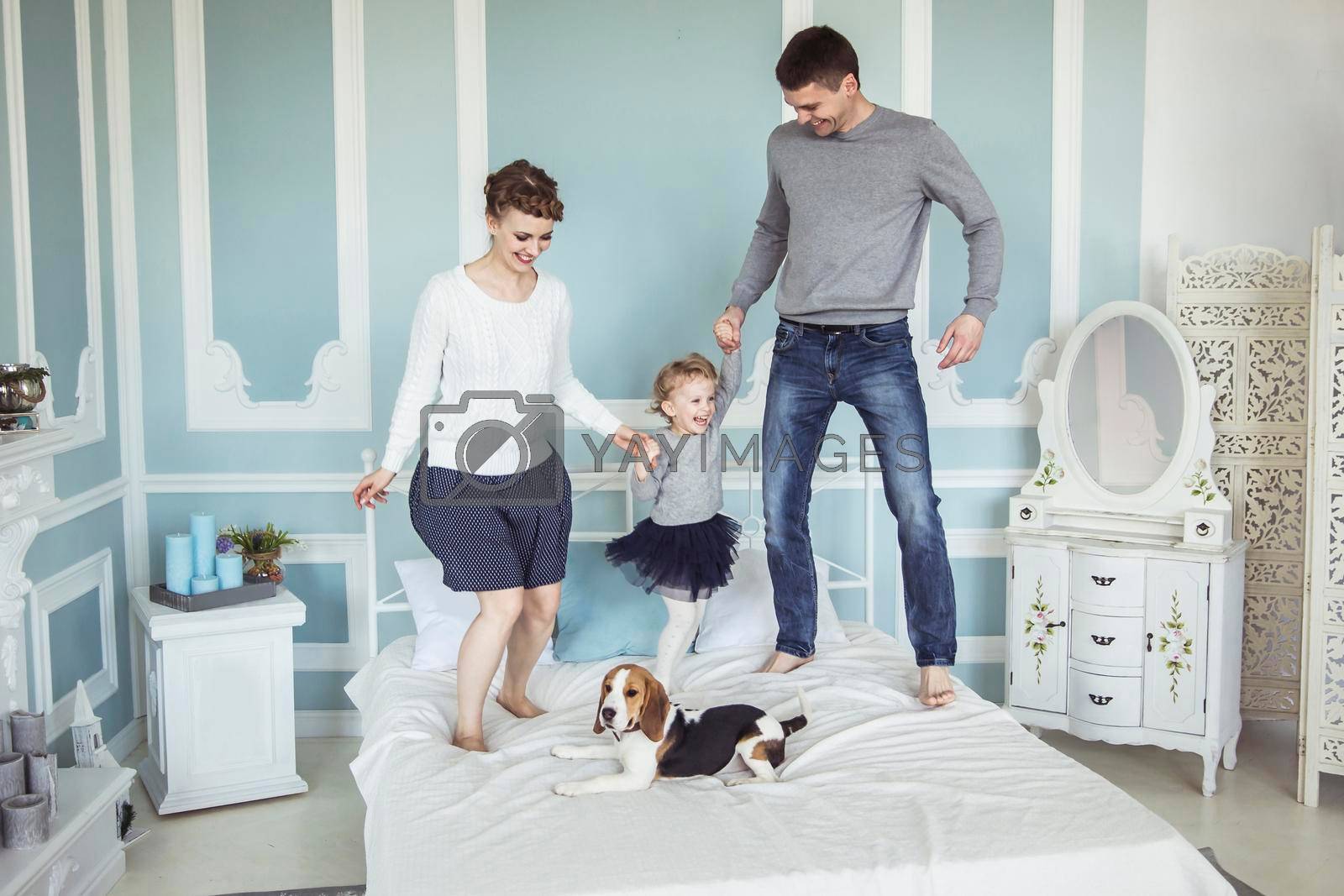 Royalty free image of concept of family happiness: loving parents playing with baby daughter on bed in bedroom by SmartPhotoLab