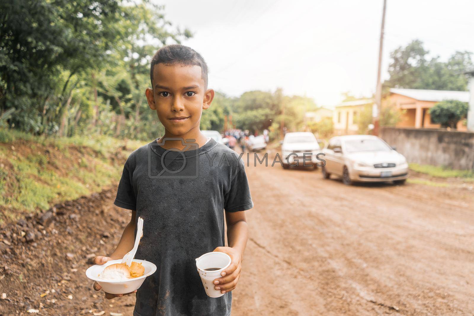Royalty free image of Nicaraguan boy holding a plate with nacatamal and a glass with coffee during a local celebration by cfalvarez