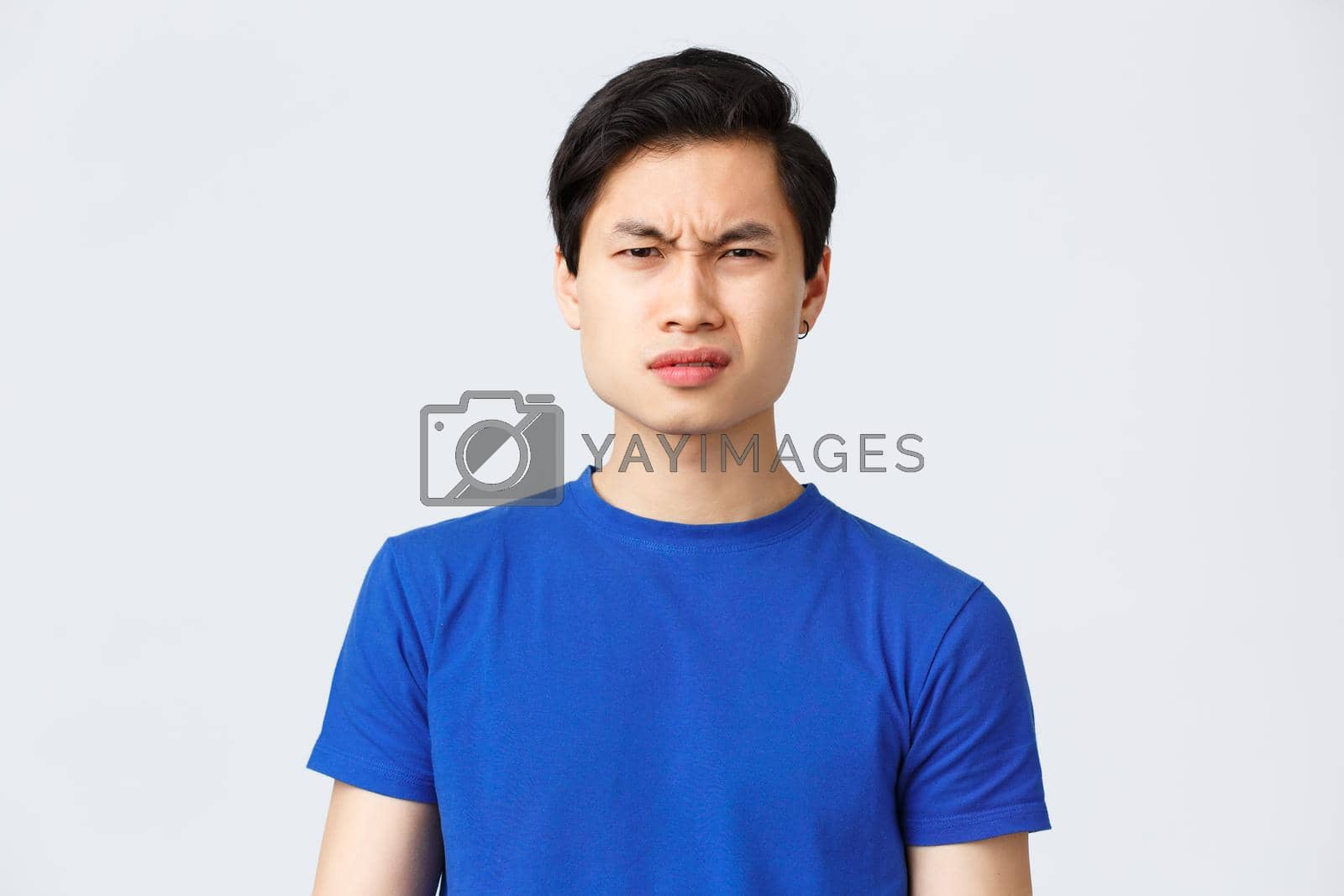 Royalty free image of Lifestyle, people emotions and beauty concept. Wtf going on. Frustrated and puzzled asian guy in blue t-shirt frowning, grimacing confused cant understand what happened, stand grey background by Benzoix