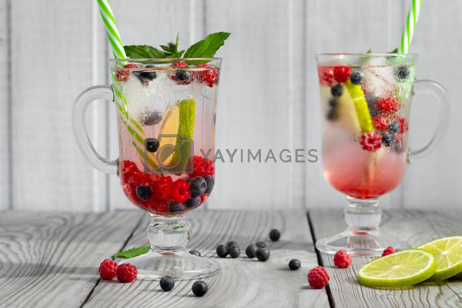 Royalty free image of Fresh homemade summer cocktails with ice, lime and berries in glasses with a straw by galsand