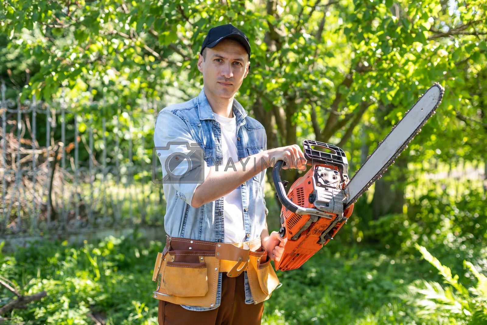 Royalty free image of man sawing branches with a chainsaw. Concept of a professional logging by Andelov13