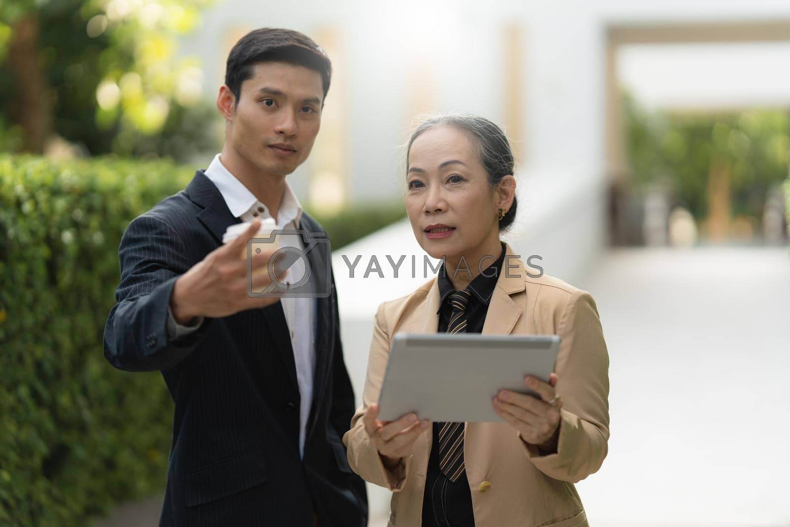 Royalty free image of Portrait of Asian Senior Business woman and young business man discussing about project by digital tablet. Account and Finance concept. by itchaznong