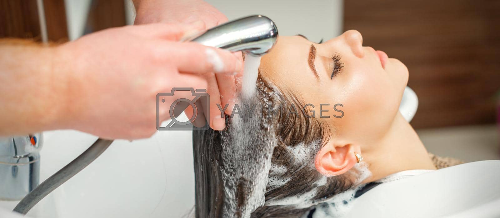 Royalty free image of Hands of hairdresser washing hair of woman by okskukuruza