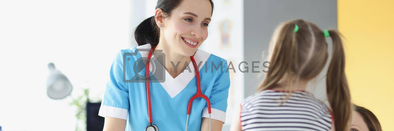 Royalty free image of Smiling professional pediatrician talk to young cute patient girl on appointment by kuprevich