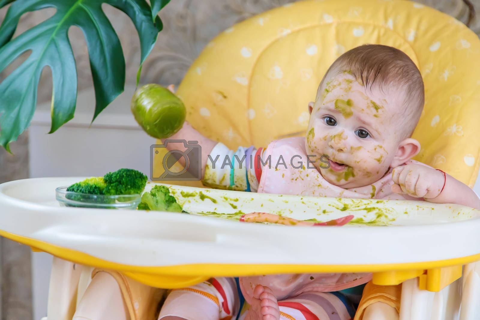 Royalty free image of Little baby eats broccoli puree himself. Selective focus. by yanadjana