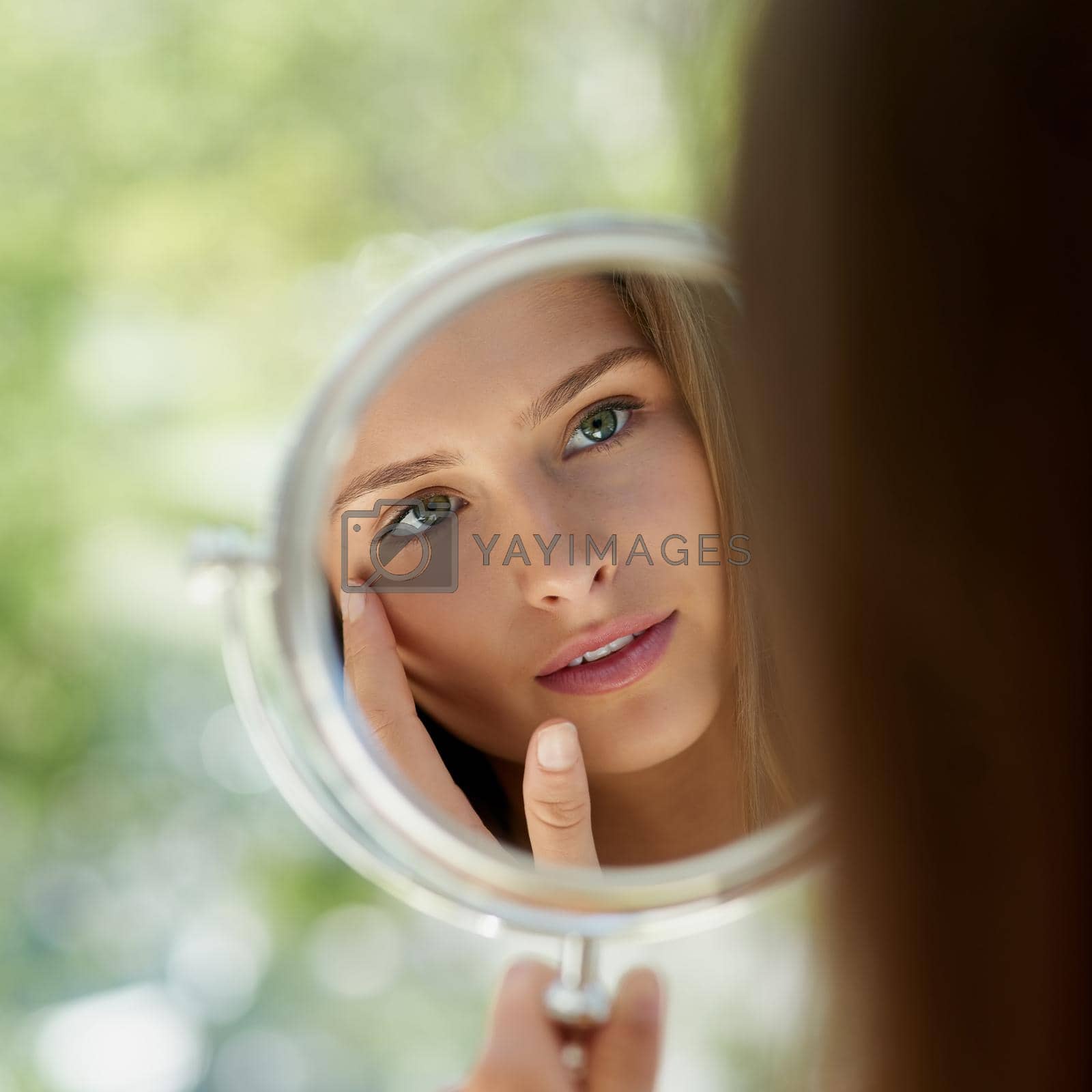 Royalty free image of The health of her skin is clear to see. Shot of an attractive young woman touching her skin in front of the mirror. by YuriArcurs
