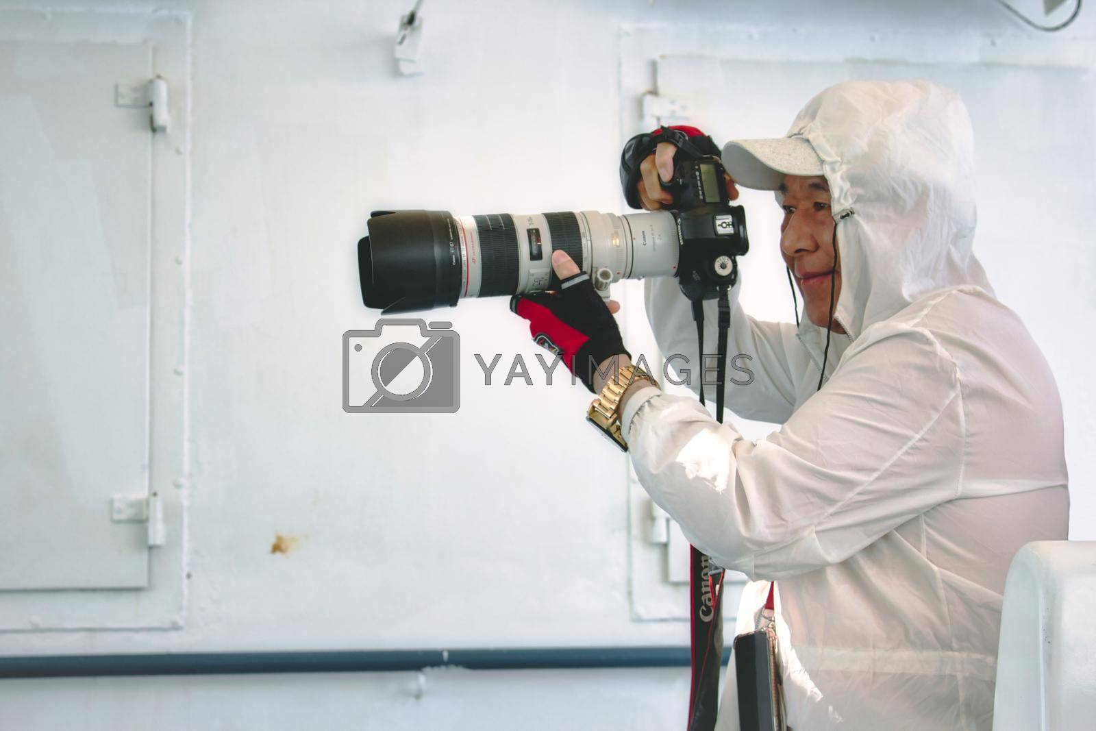 Royalty free image of Gozo / Malta - June 28 2019: A Japanese man taking a picture on board the Gozo/Malta ferry with a professional Canon long-range camera by tennesseewitney