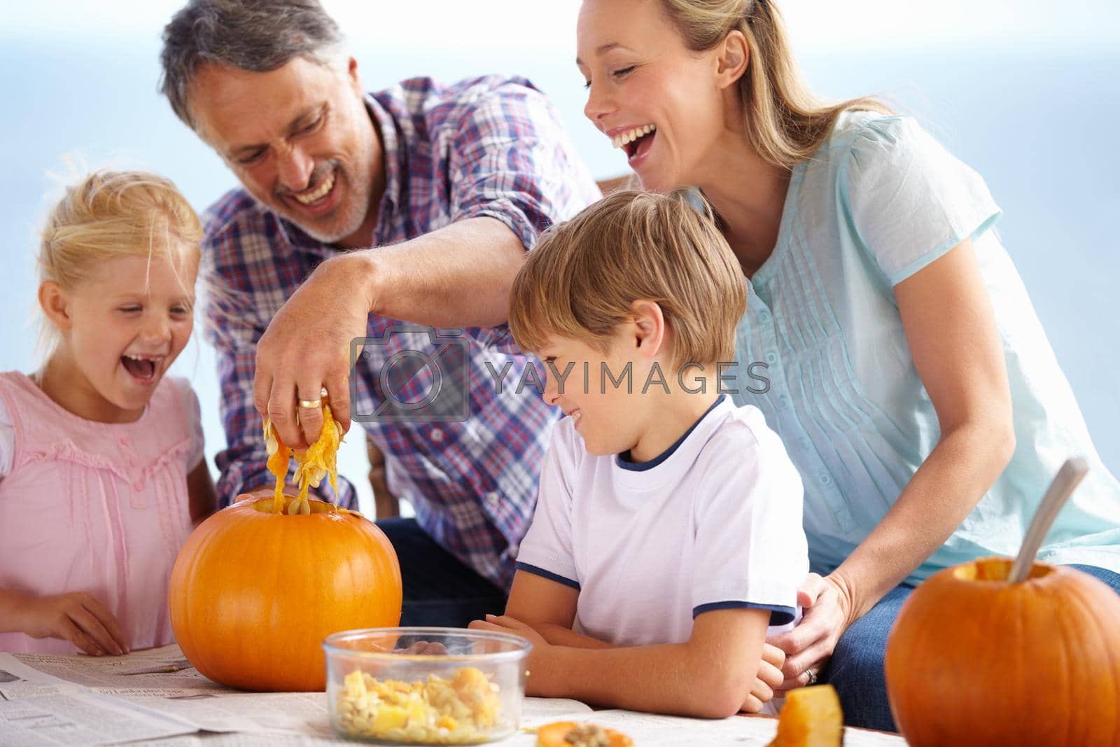Royalty free image of Getting into the spirit of halloween. A family of four carving pumpkins at home. by YuriArcurs