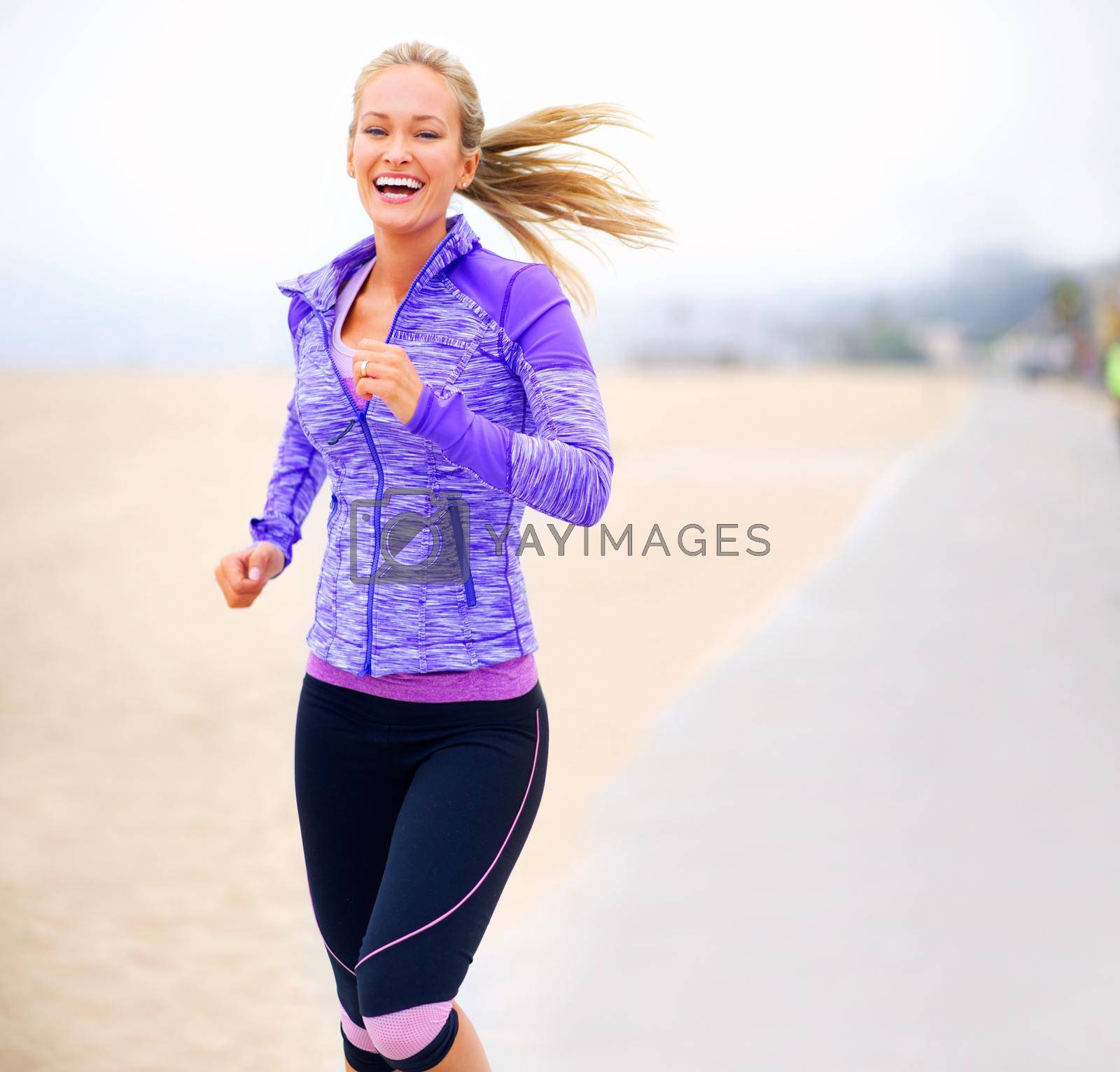 Royalty free image of Im pumped for this run. Portrait of a young woman jogging near the beach. by YuriArcurs
