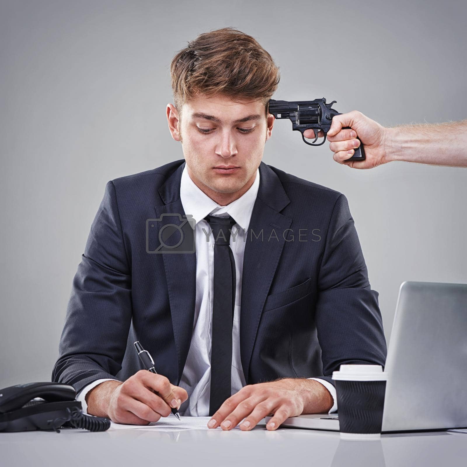 Royalty free image of Being forced to sign the papers. A business man signing a piece of paper with someone pointing a gun at his head. by YuriArcurs
