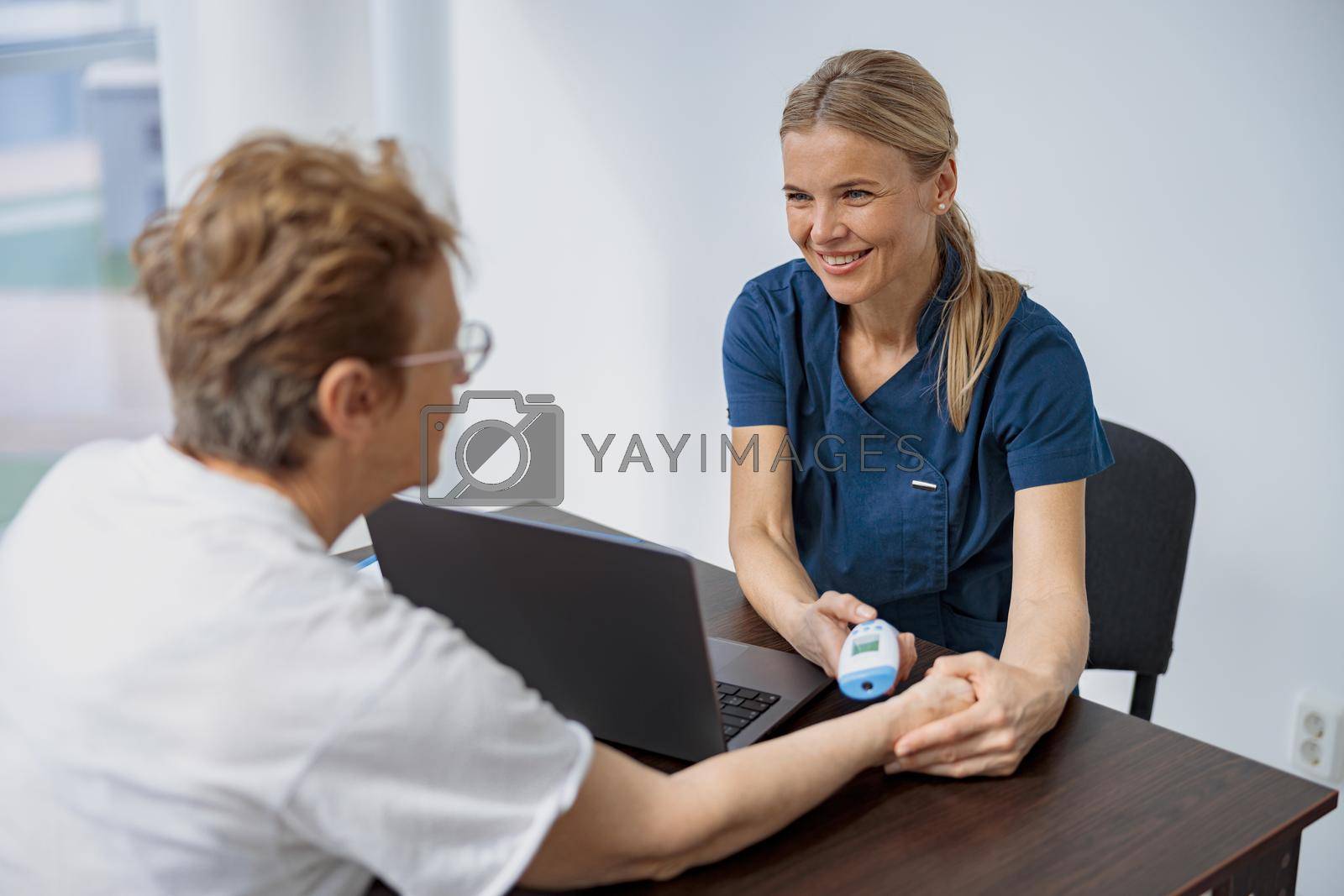 Royalty free image of Doctor measures patient's temperature with non-contact thermometer during an appointment by Yaroslav_astakhov