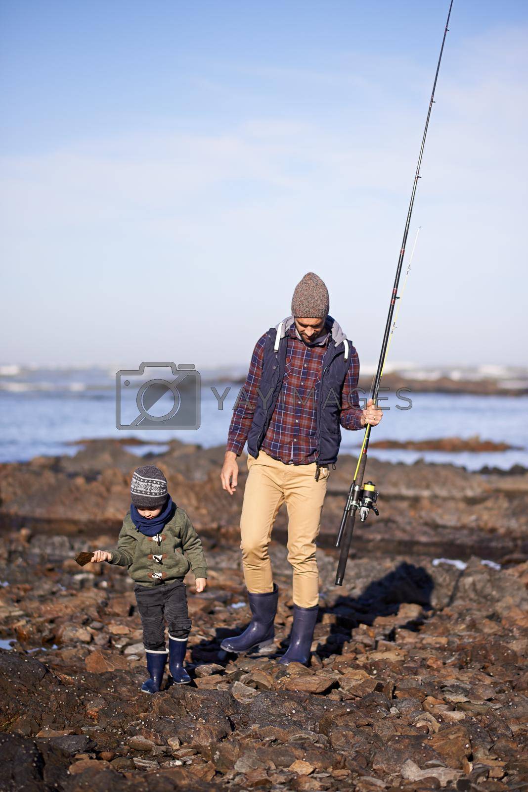 Royalty free image of Doing some father and son bonding. Shot of a father and son walking on the rocks while out fishing together by the sea. by YuriArcurs