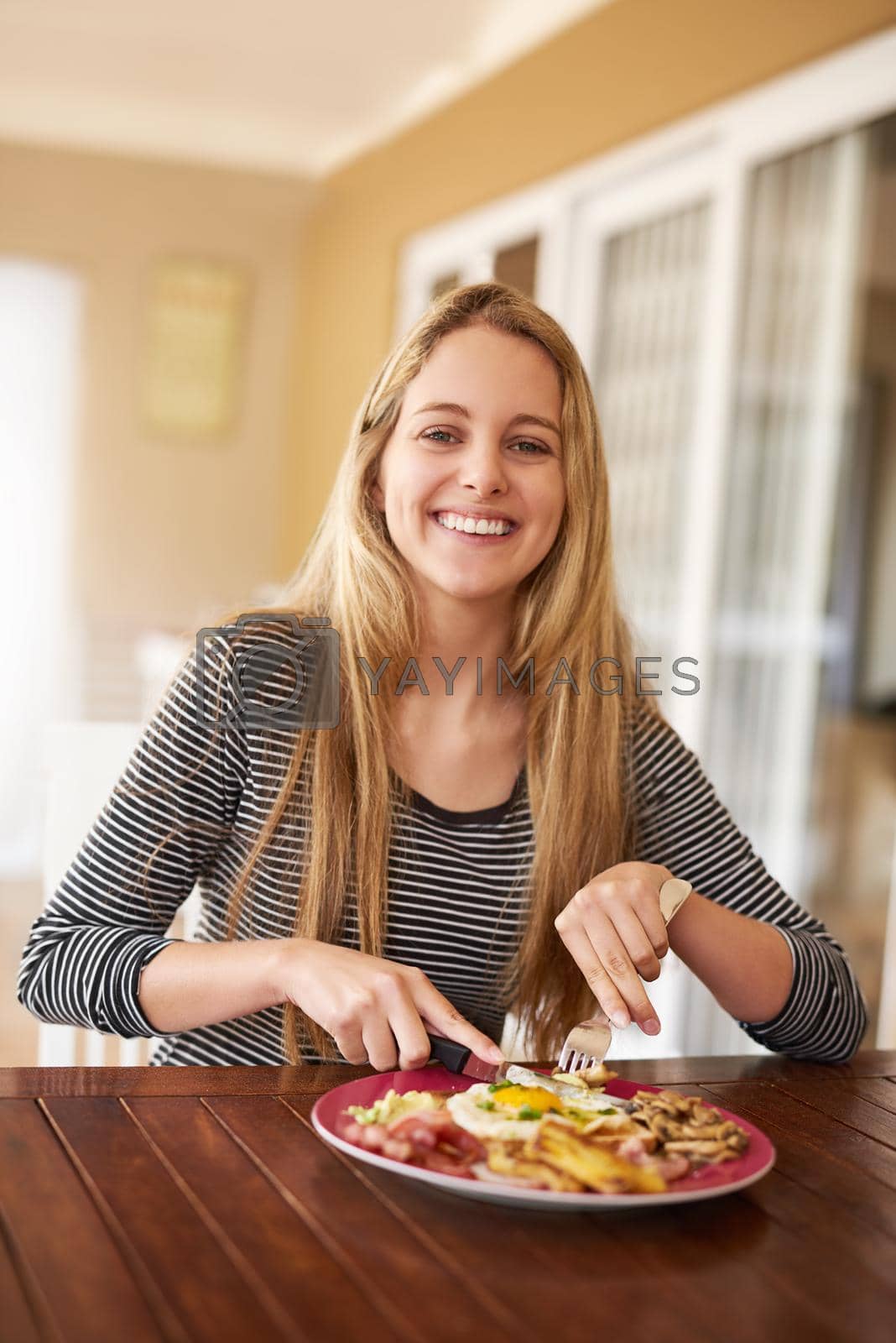 Royalty free image of Having a delicious start to the day. Shot of a happy young woman enjoying a meal at home. by YuriArcurs