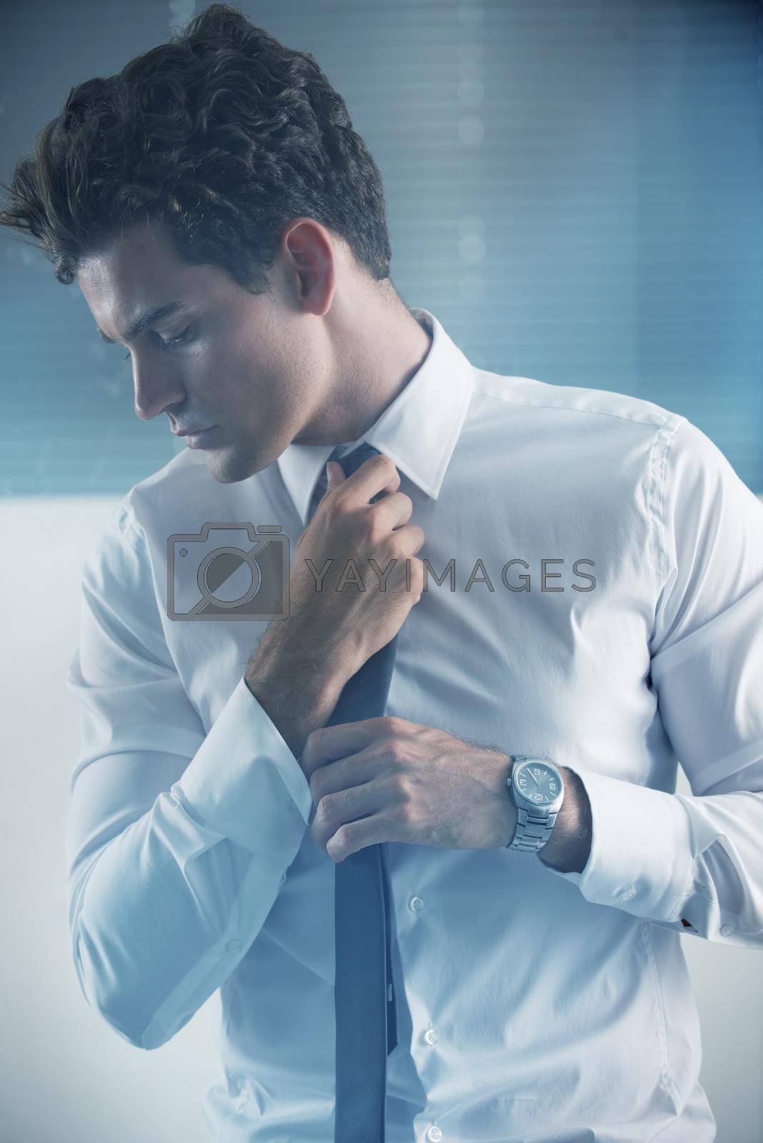 Royalty free image of White collar confidence. Cropped shot of a handsome young businessman getting ready for work. by YuriArcurs