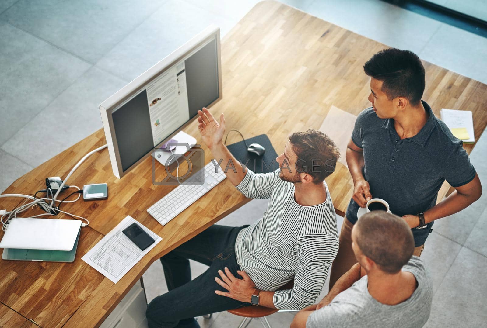 Royalty free image of Working together to achieve the end product the client wants. High angle shot of three designers working together on a project in an office. by YuriArcurs