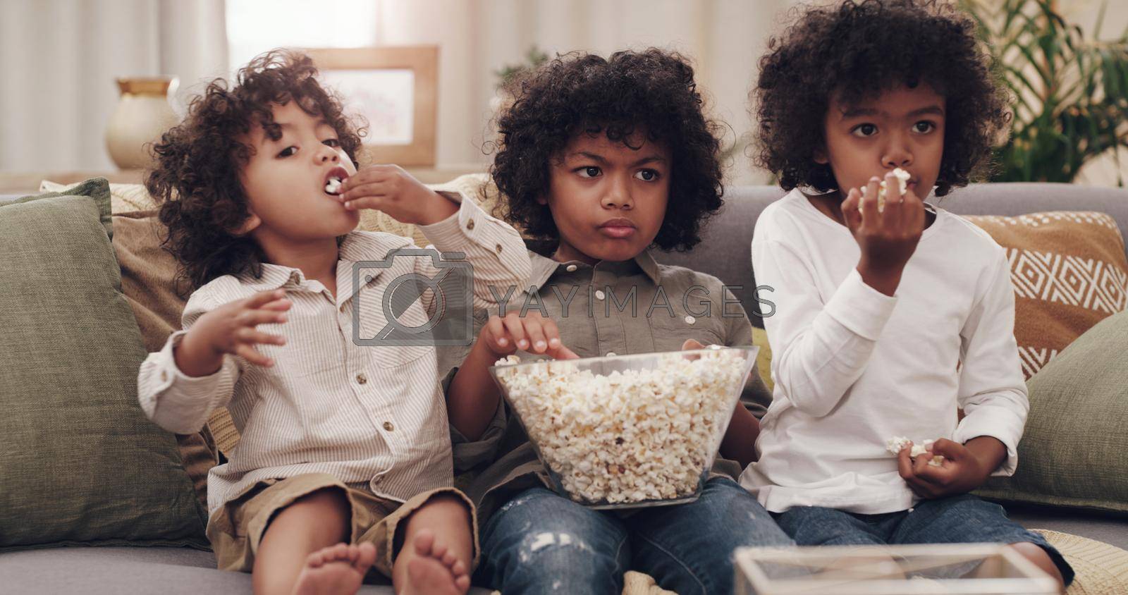 Royalty free image of Whats a movie without snacks. Shot of three adorable little boys eating popcorn and watching movies together at home. by YuriArcurs