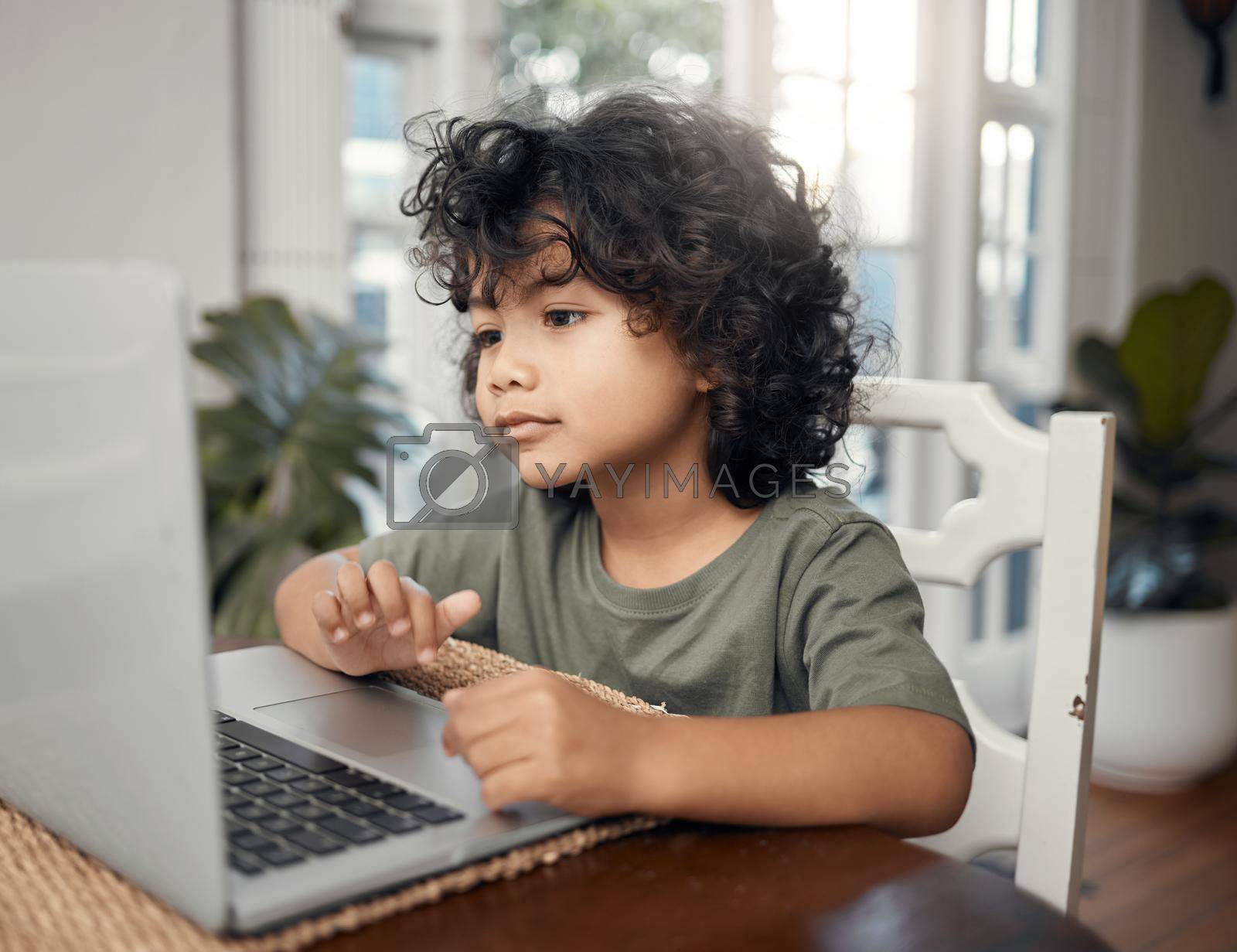Royalty free image of Learning with my favourite character. Shot of an adorable little boy using a laptop while sitting at home. by YuriArcurs