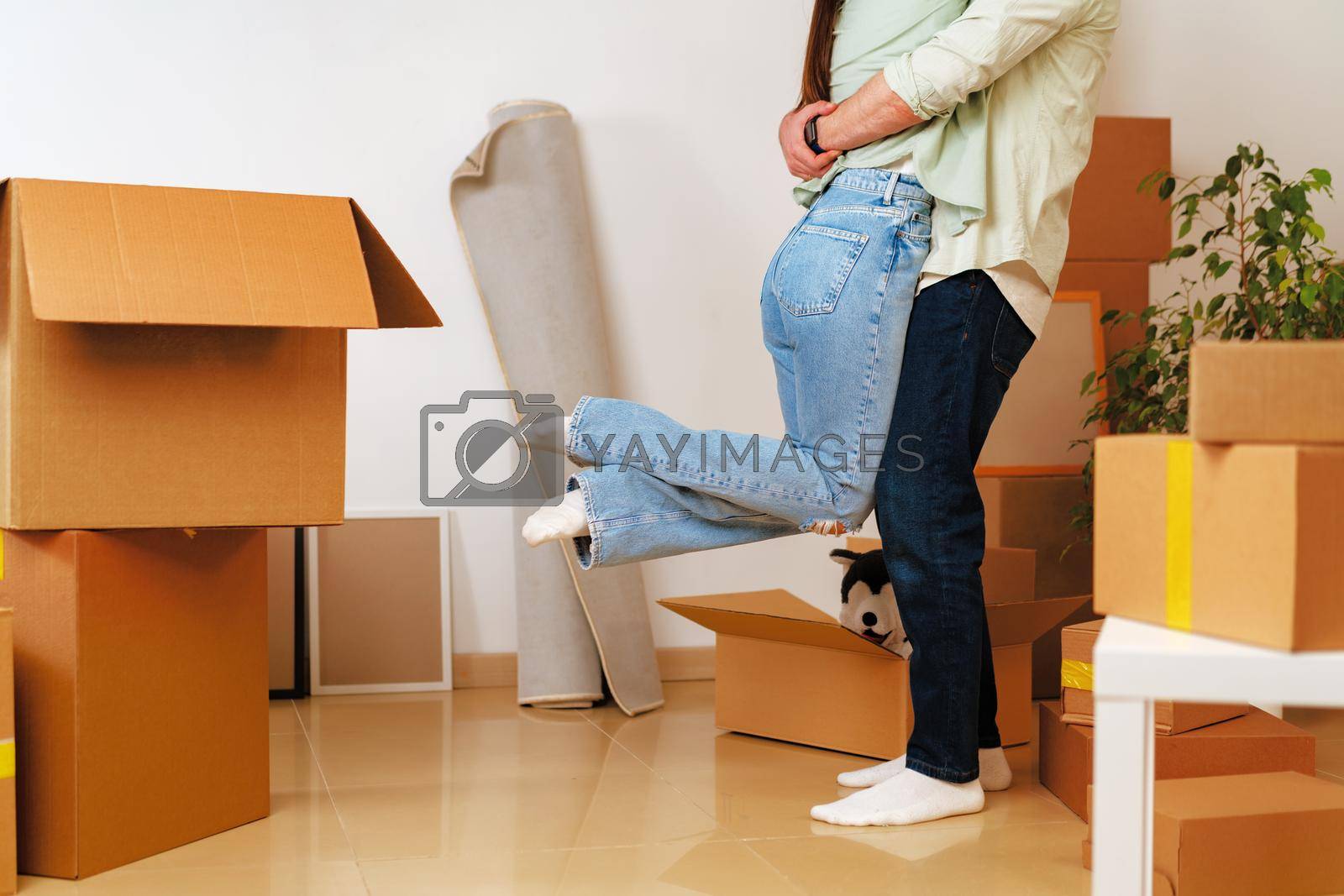 Royalty free image of Young happy couple in room with moving boxes at new home by Fabrikasimf
