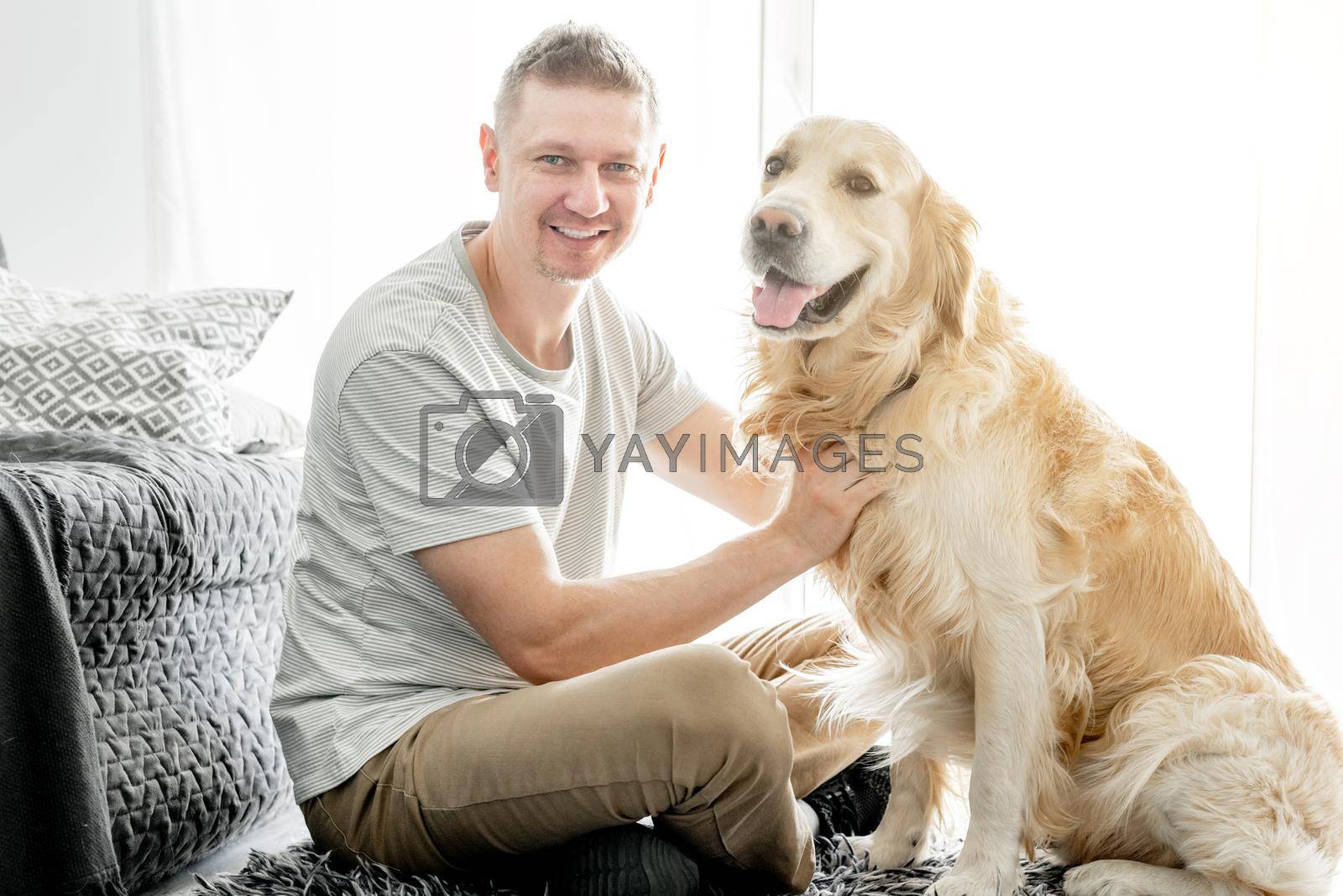 Royalty free image of Young handsome man with his golden retriever dog by tan4ikk1
