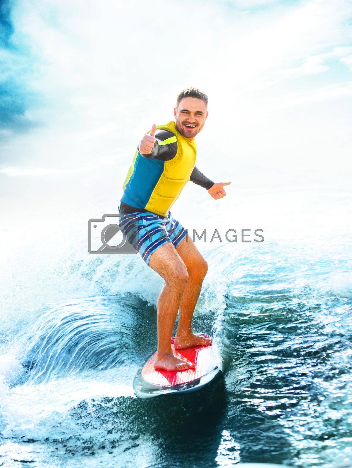 Royalty free image of Surfing, blue ocean. Young Man show thumbs up on wakeboard. by MikeOrlov