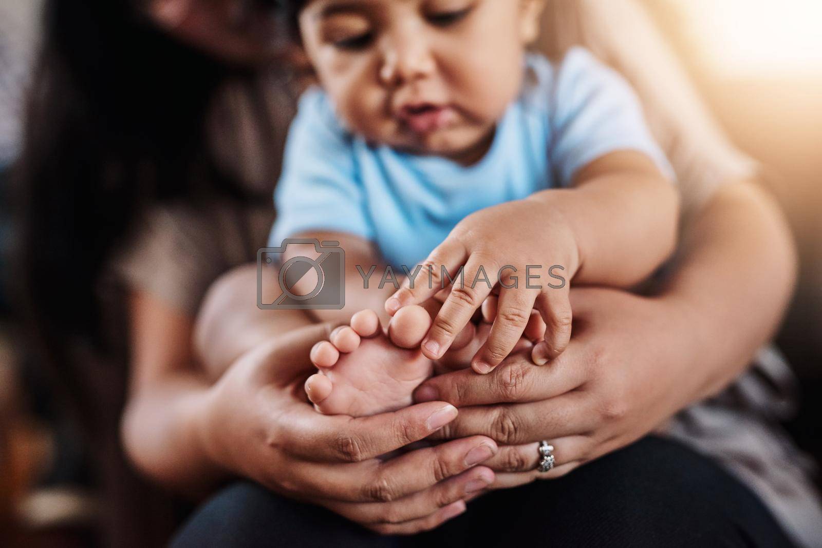Royalty free image of This little piggy went all the way home. Closeup of an unrecognizable woman holding her childs feet while being seated on a sofa at home during the day. by YuriArcurs