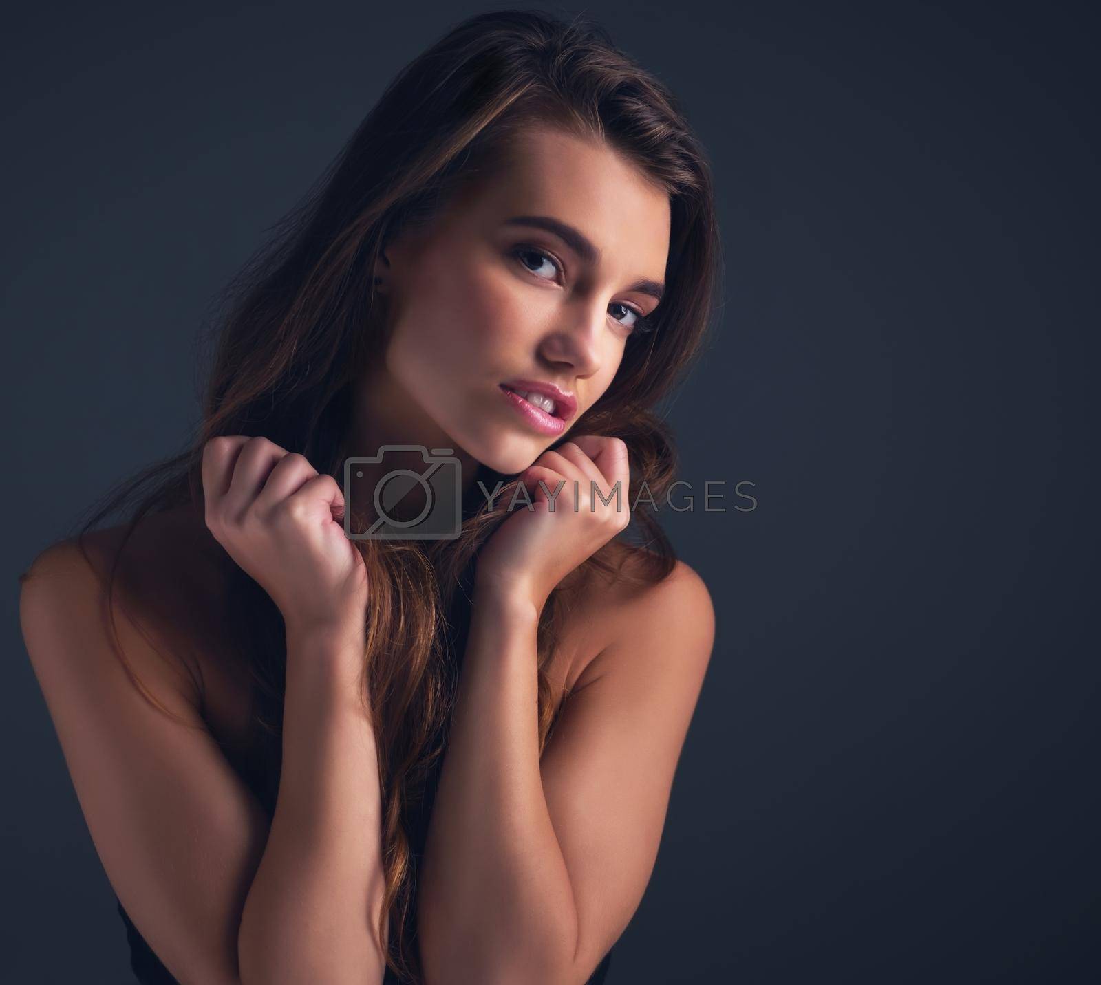Royalty free image of There is innocence in her beauty. Studio shot of an attractive young woman posing against a dark background. by YuriArcurs