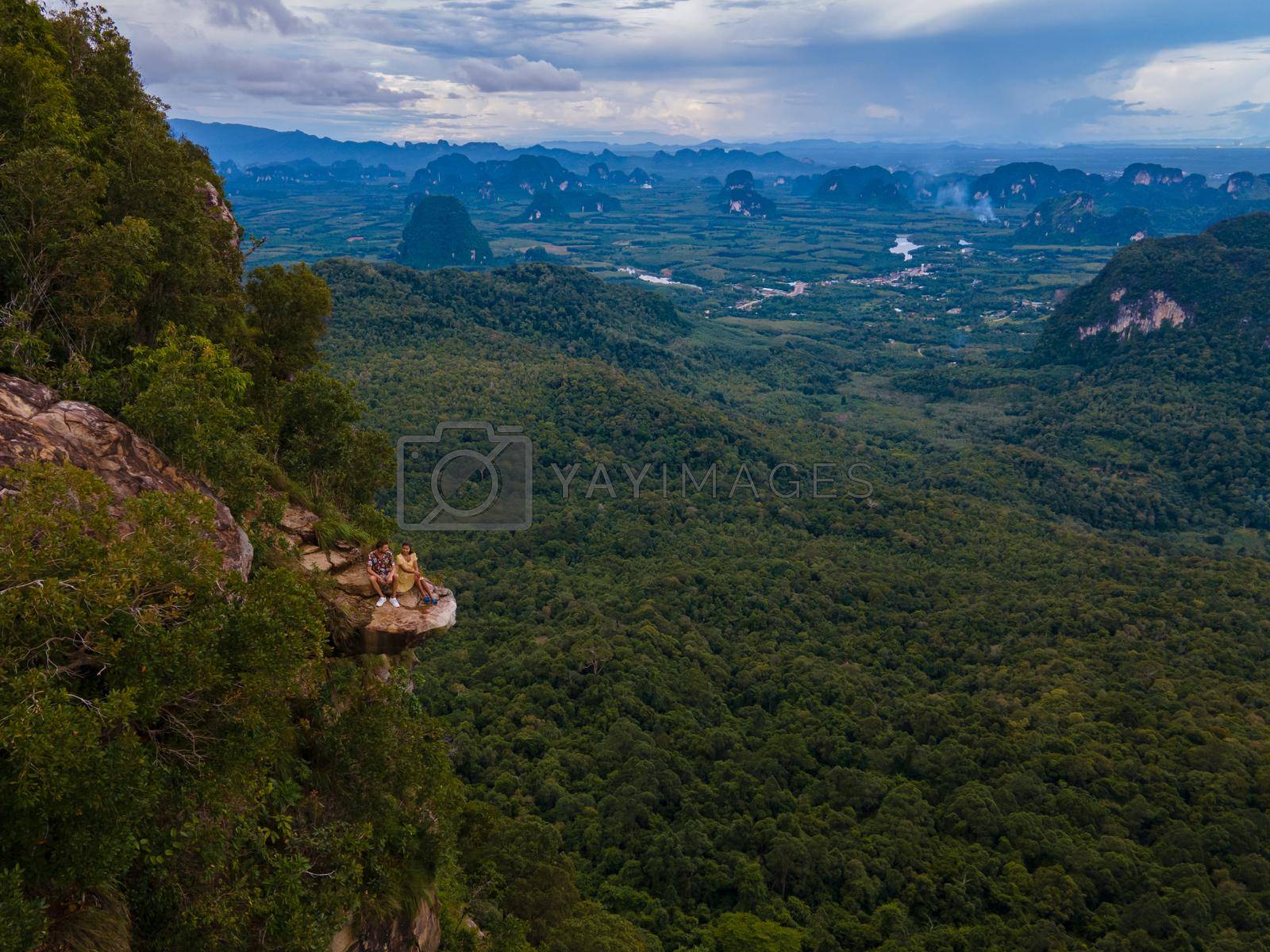 Royalty free image of Dragon Crest mountain Krabi Thailand, a Young traveler sits on a rock that overhangs the abyss, with a beautiful landscape. Dragon Crest or Khuan Sai at Khao Ngon Nak Nature Trail by fokkebok