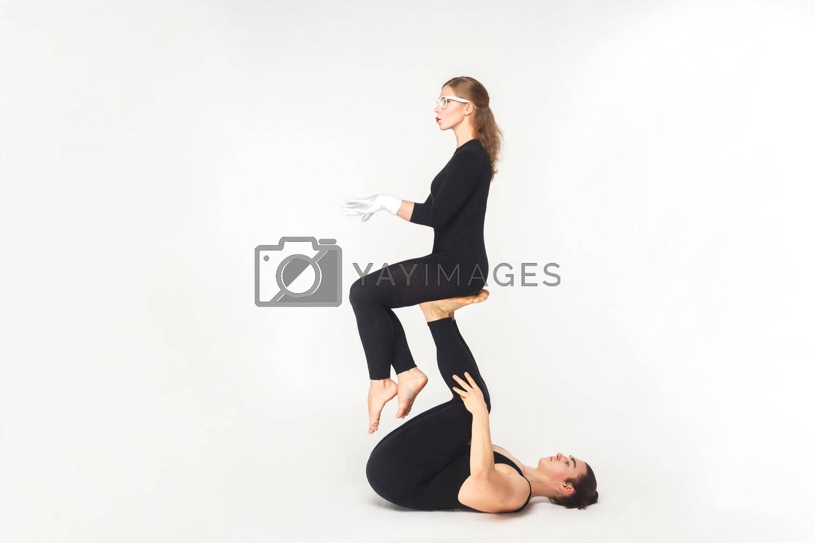 Royalty free image of Acrobatic concept, sit pose. Young man holding woman legs, balancing. by Khosro1