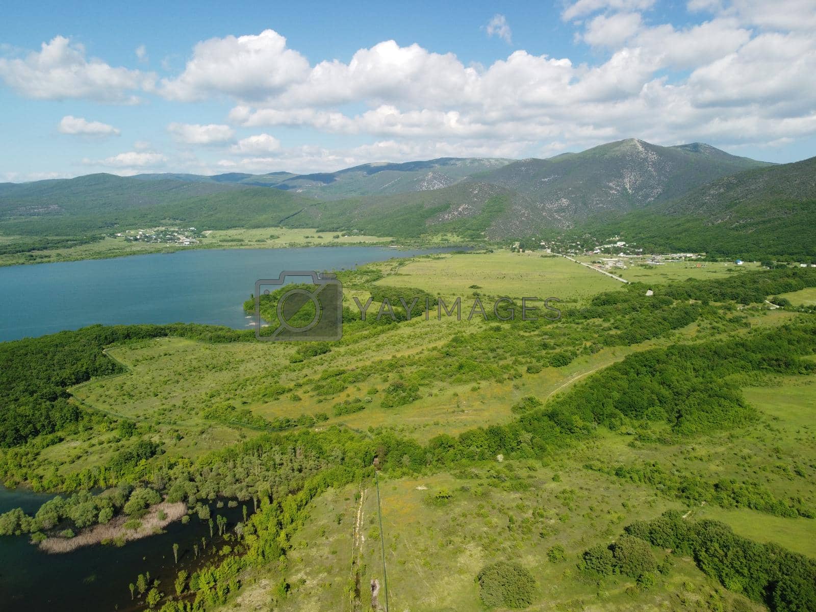 Royalty free image of Aerial view on water reservoir at mountain valley covered with green spring forest. Beautiful view from above on smooth blue surface of mountain lake among highlands. Drone point of view. Nobody by panophotograph