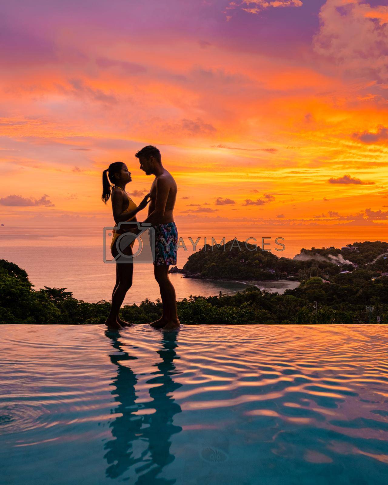 Royalty free image of couple European man and Asian woman in infinity pool in Thailand looking out over the ocean, luxury vacation in Thailand by fokkebok