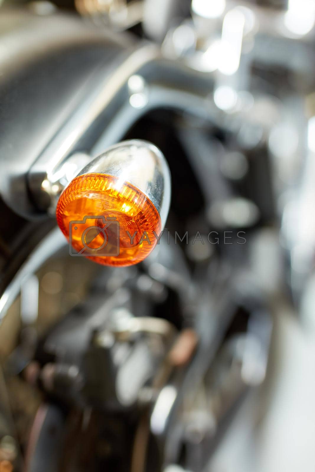 Royalty free image of Closeup rear view of a taillight on a motorbike. Orange turning light on a blurred black vintage motorcycle. One modern chrome transportation vehicle. Maintenance on a shiny classic retro custom bike by YuriArcurs