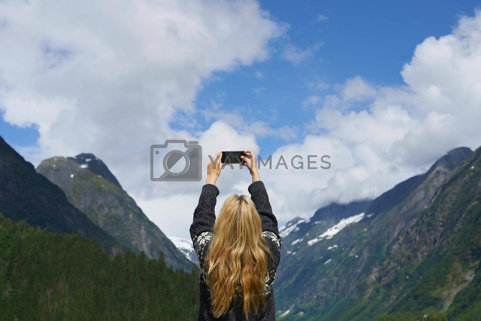 Adventure woman taking photo smart phone of glacial valley landscape on travel exploration for social media.