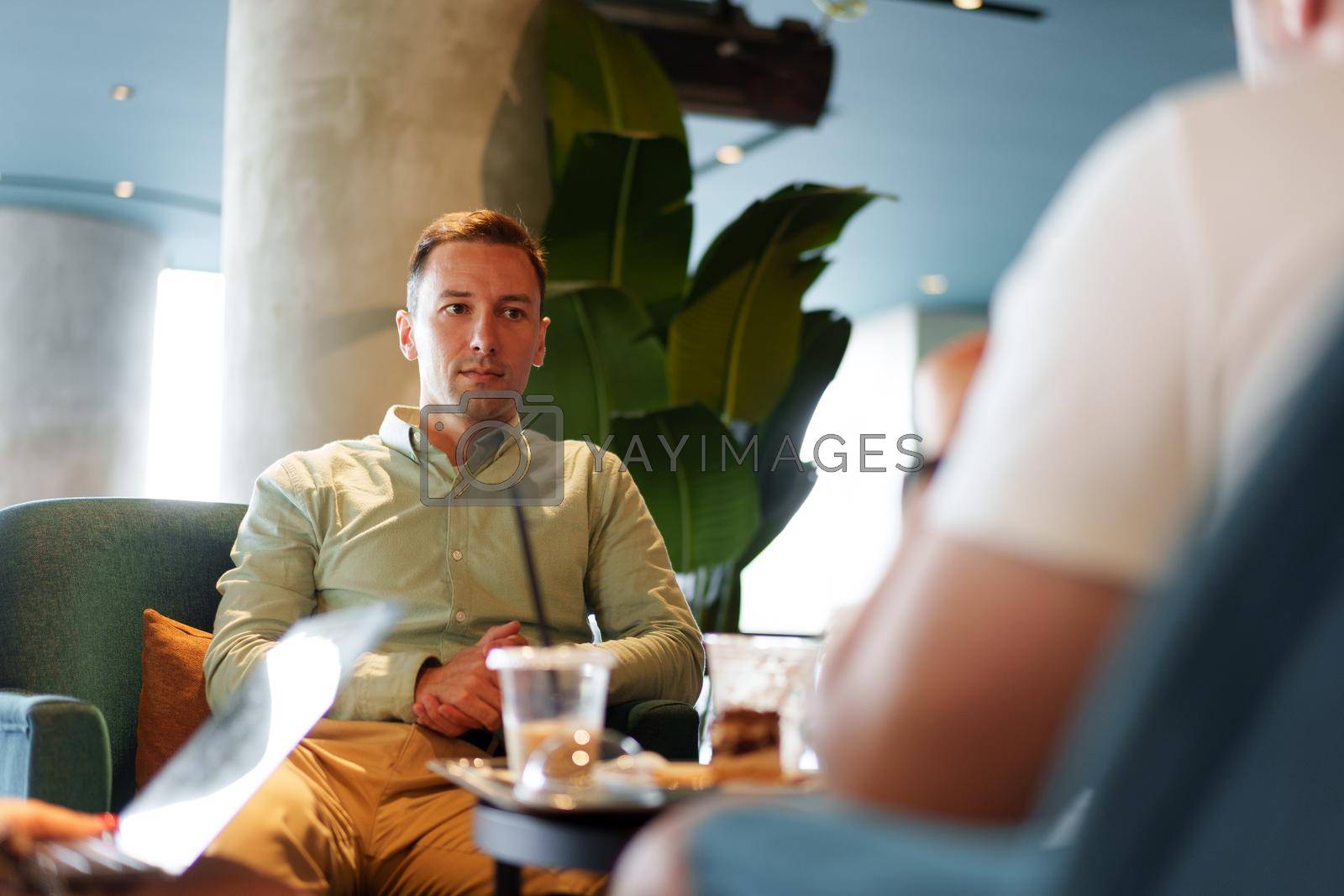 Royalty free image of Confident young businessman sitting at street cafe by Fabrikasimf
