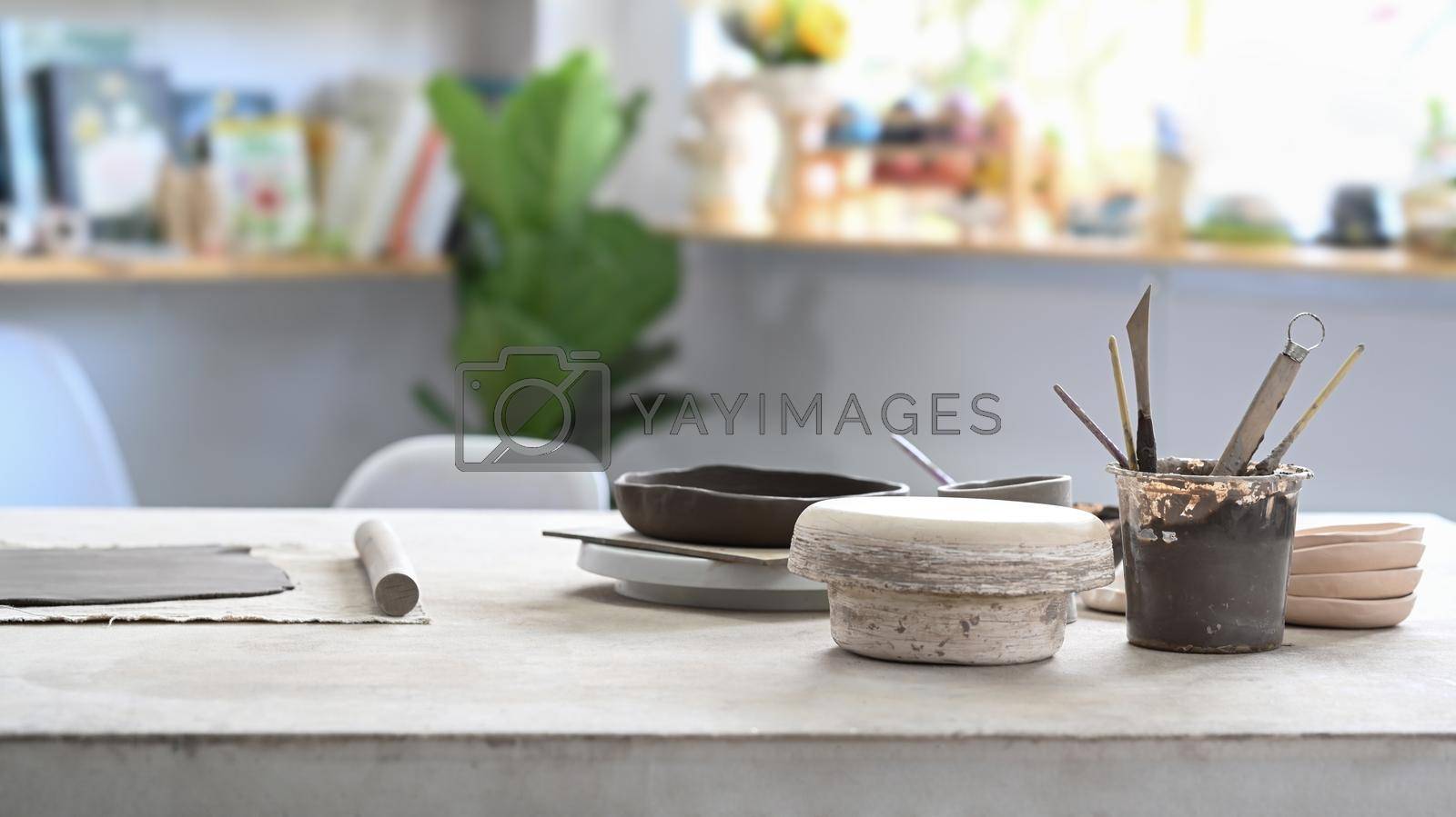 Royalty free image of Set of clay products, stacking on white table in pottery workshop by prathanchorruangsak